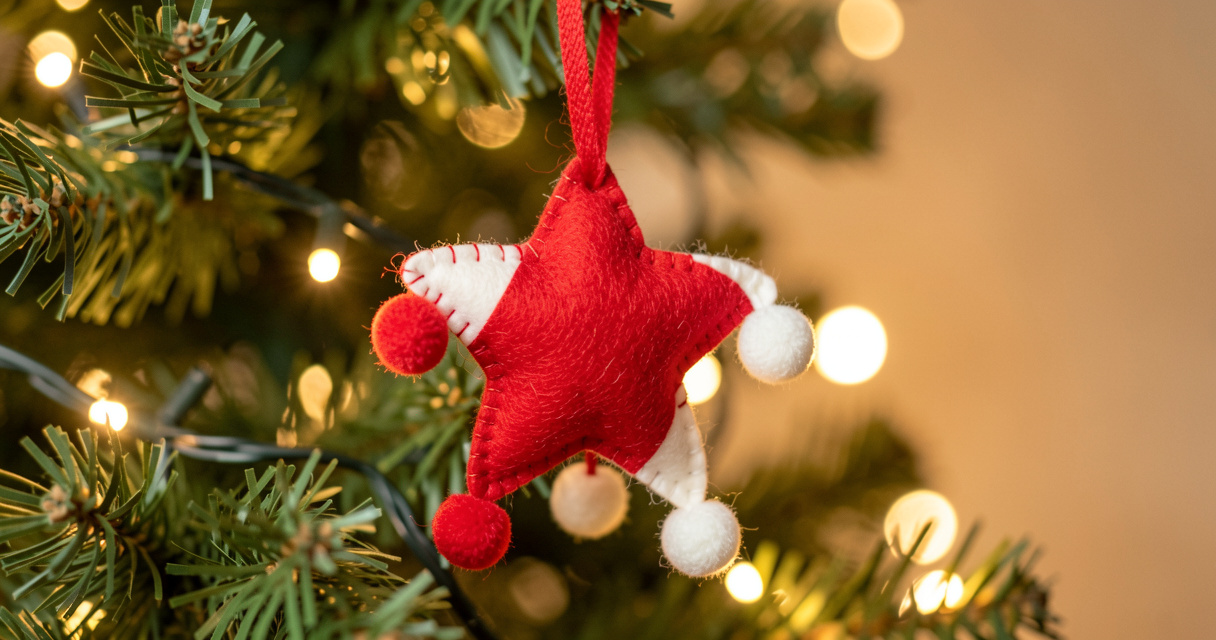 Adorno navideño de fieltro en forma de estrella decorado con pompones colgado en el árbol